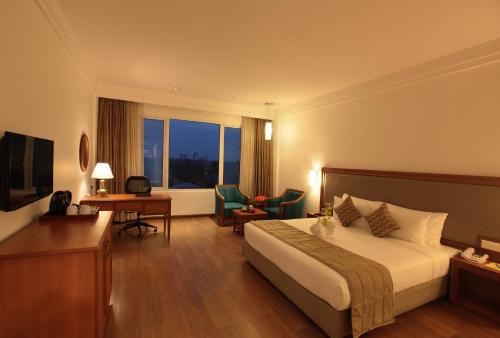 a hotel room with a bed and a television at Monsoon Empress Kochi in Cochin