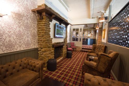 a waiting room with a stone fireplace and chairs at Dragonfly Hotel Colchester in Colchester