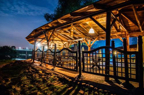 a wooden pavilion with lights on the water at night at Hotel Zamek Pułtusk Dom Polonii in Pultusk