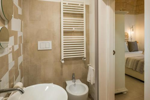 a bathroom with a sink and a toilet and a bed at Amatè Suite in Lecce