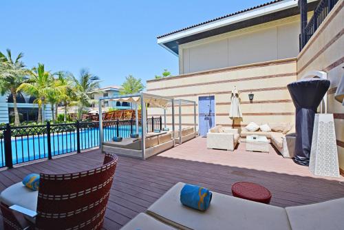 eine Terrasse mit einem Tisch, Stühlen und einem Pool in der Unterkunft Zabeel Saray Royal Residences Lagoon Villa in Dubai