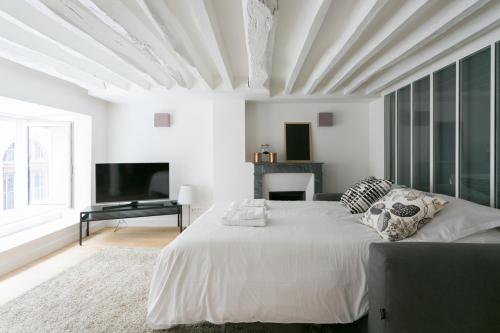 une chambre blanche avec un grand lit et une télévision dans l'établissement Lafayette Private Apartment, à Paris
