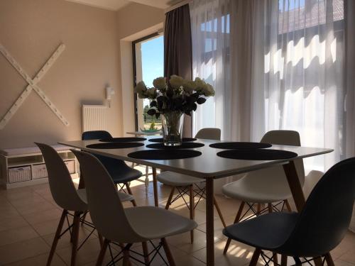 een eettafel met stoelen en een vaas met bloemen bij Balticsand Apartament in Mielno