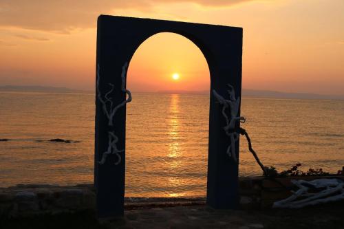 an arch on the beach with the sunset in the background at Villas Agapitos in Ayios Nikolaos Sithonia
