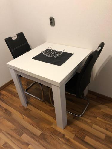 kleine Ferienwohnung في Inzlingen: طاولة بيضاء مع كرسيين في الغرفة