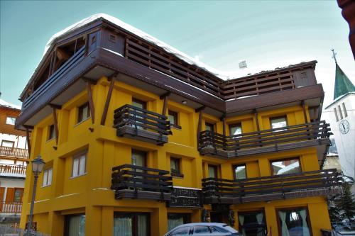 a yellow building with wooden balconies on it at Hotel Meynet in Breuil-Cervinia
