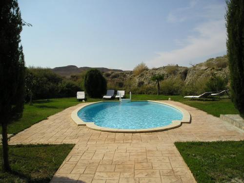 una piscina con 2 sillas en un patio en Hotel Cueva Tardienta Monegros-Adults Only, en Tardienta