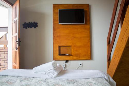 a room with two beds and a tv on a wall at Pousada Estrelas no Mar Florianópolis in Florianópolis