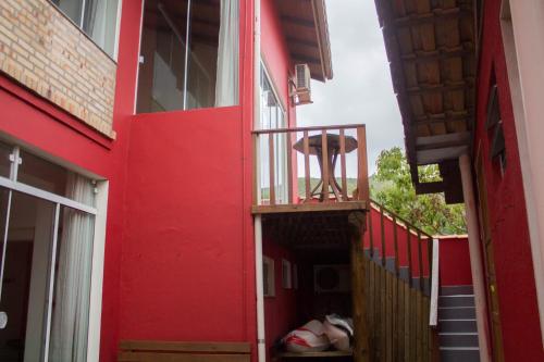 a red building with a red door and a chair on a balcony at Pousada Estrelas no Mar Florianópolis in Florianópolis