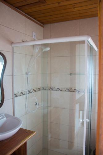 a shower with a glass door next to a sink at Pousada Estrelas no Mar Florianópolis in Florianópolis