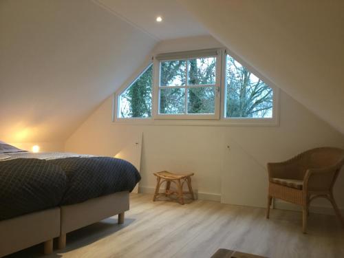 an attic bedroom with a bed and a window at De Fugelsang in Jonkersland