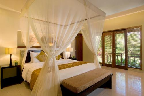 - une chambre avec un lit à baldaquin dans l'établissement The Kunja Villa-Hotel, à Seminyak