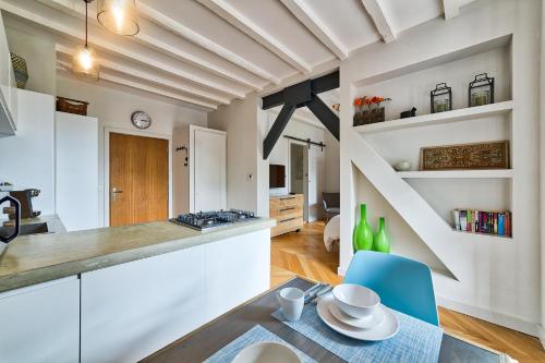une cuisine avec des placards blancs, une table et des chaises bleues dans l'établissement Marie Paradis Studio Apt 15, à Chamonix-Mont-Blanc
