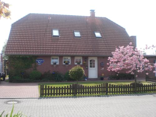 uma casa com uma cerca e uma árvore rosa florida em Ferienwohnung "Kleine Krabbe" em Werdum