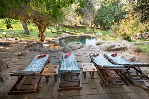 a group of three chairs and a swimming pool at Blyde River Wilderness Lodge in Hoedspruit