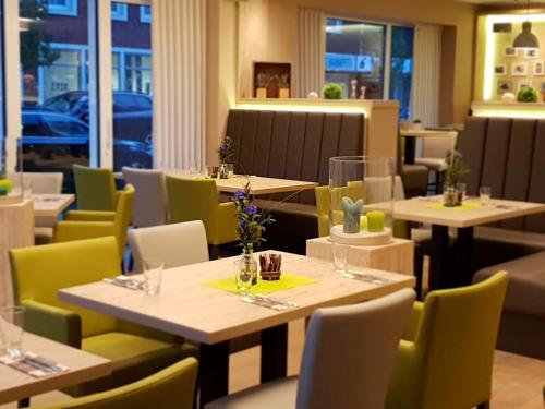 un restaurante con mesas de madera y sillas amarillas en Hotel Clemenswerther Hof en Sögel