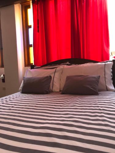 a bed with black and white striped sheets and red curtains at Villa Pepita Real in Villa de Leyva