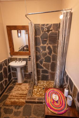 a bathroom with a shower with a stone wall at Blyde River Wilderness Lodge in Hoedspruit