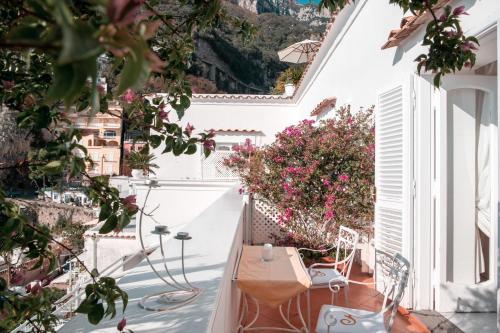 a balcony with flowers and a table and chairs at Villa Yiara in Positano