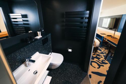 a bathroom with a white sink and a toilet at Hotel Le Bugatti in Molsheim