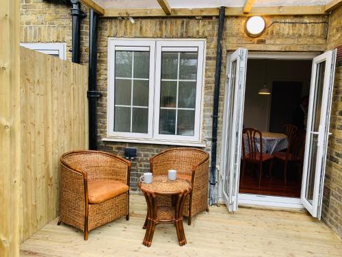 a patio with two wicker chairs and a table at Tapestry Apartment in London