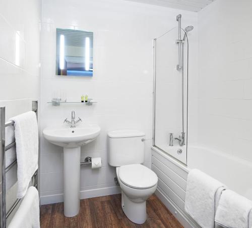 a white bathroom with a toilet and a sink at The Bridge House; BW Signature Collection in Ferndown