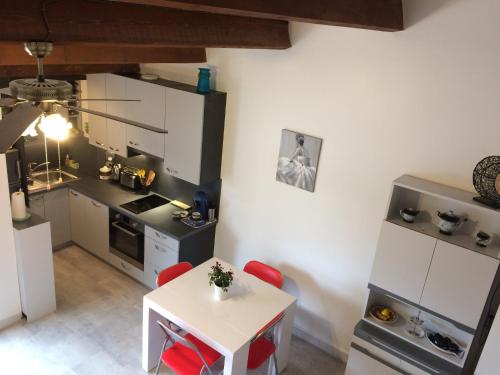 une petite cuisine avec une table blanche et des chaises rouges dans l'établissement Le P’tit Littoral, au Grau-dʼAgde