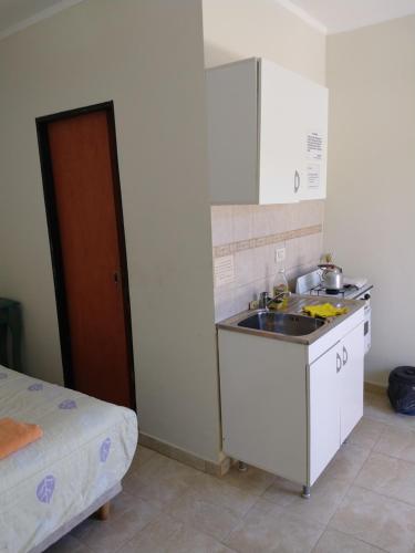 a small kitchen with a sink and a bed at El Sueño de Pedro - Pileta Climatizada in Colón