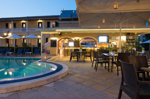 un patio del hotel con piscina, mesas y sillas en Solaris Apartment Kassiopi, en Kassiopi