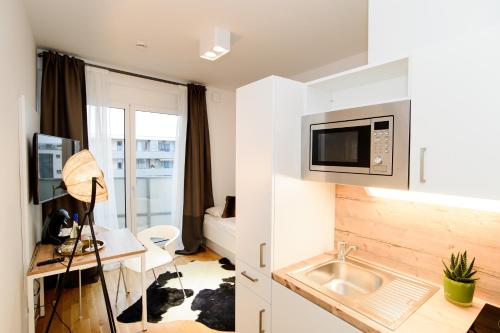 a small apartment with a desk and a microwave at Apart Hotel Messe Munich - my room Apartments in Munich