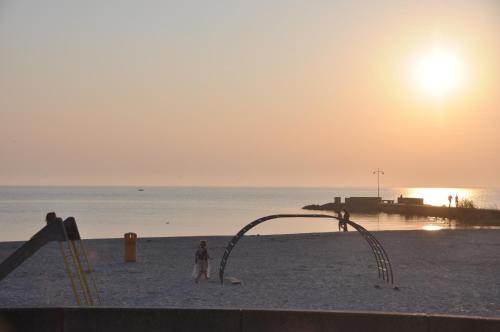 a child standing on a beach with a playground at Strandhotel Vigilante in Makkum