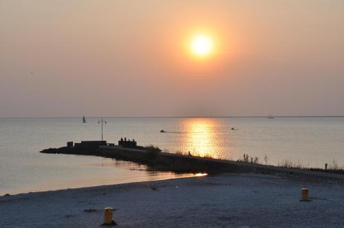 a sunset over a body of water with a fire hydrant at Strandhotel Vigilante in Makkum