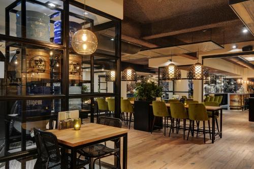 a restaurant with tables and chairs and a bar at Strandhotel Vigilante in Makkum