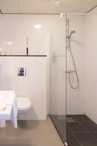 a bathroom with a toilet and a glass shower at Strandhotel Vigilante in Makkum