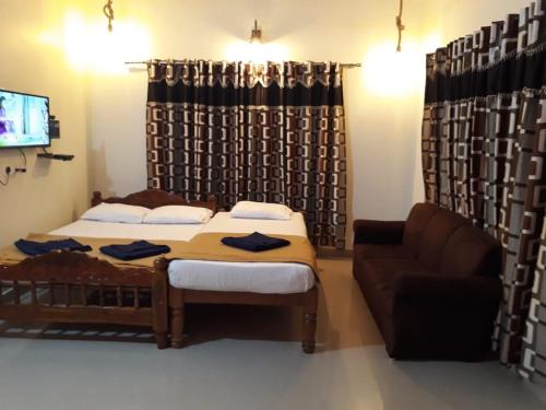 a bedroom with a bed and a couch and a television at 5 Mile Beach Resort in Kumta