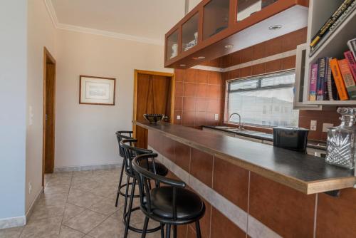 a kitchen with a bar with stools and a sink at Chala-Kigi Apartments in Swakopmund