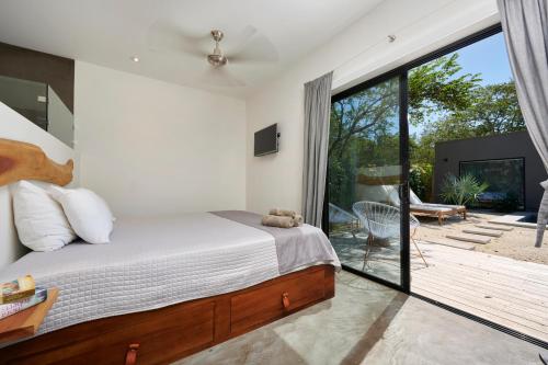 a bedroom with a bed and a sliding glass door at Villa Ethir in Tamarindo