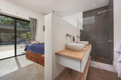 a bathroom with two sinks and a shower and a bed at Villa Ethir in Tamarindo