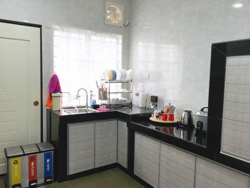 - une cuisine avec un comptoir noir et un évier dans l'établissement Bukit Katil Indah Homestay, à Malacca