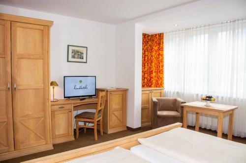 a room with a desk with a television and a bed at Landhotel Post Ebensee am Traunsee ***S in Ebensee