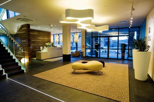 a lobby with a yellow ottoman sitting on a rug at Hotel Great Polonia Velvet Suwałki in Suwałki