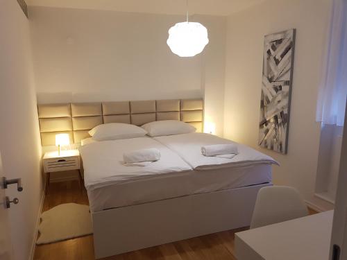 sypialnia z dużym białym łóżkiem z lampką w obiekcie HOME APARTMANI I SOBE w mieście Osijek