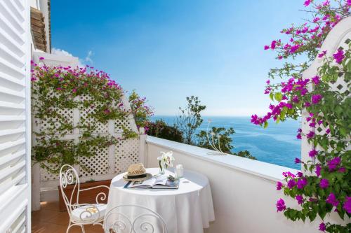 a white table and chairs on a balcony with flowers at Villa Yiara in Positano