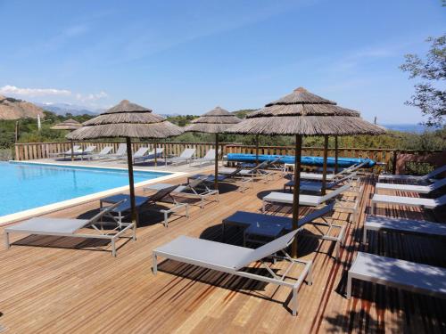 a row of lounge chairs and umbrellas next to a swimming pool at Résidence U Pirellu in Porto-Vecchio