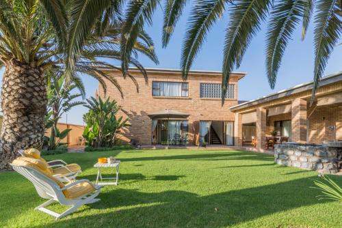 a yard with two chairs and a palm tree at Chala-Kigi Apartments in Swakopmund