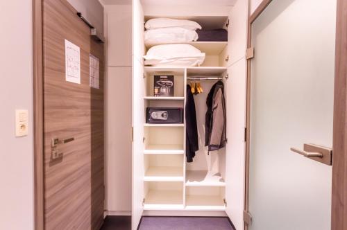 a walk in closet with white shelves and a door at ManavaHotel in Herstal