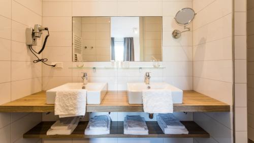 a bathroom with two sinks and a mirror at Hotel Kaap West I Kloeg Collection in Westkapelle
