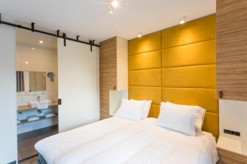 a bedroom with a large white bed with a wooden headboard at Hotel Kaap West I Kloeg Collection in Westkapelle