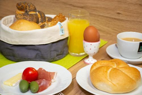 a table with a basket of breakfast foods and a cup of orange juice at Landhotel Post Ebensee am Traunsee ***S in Ebensee