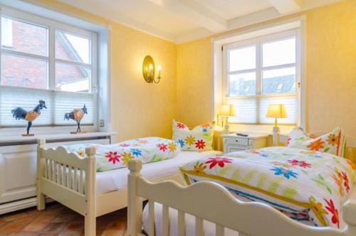 Un dormitorio con dos camas y dos ventanas. en Haus Seelord, Whg. Kapitän, en Braderup